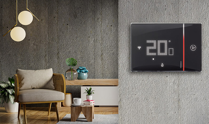 Termostato Smarther2 BTicino nero impostato a 20°C, montato su una parete in cemento in un soggiorno moderno.
