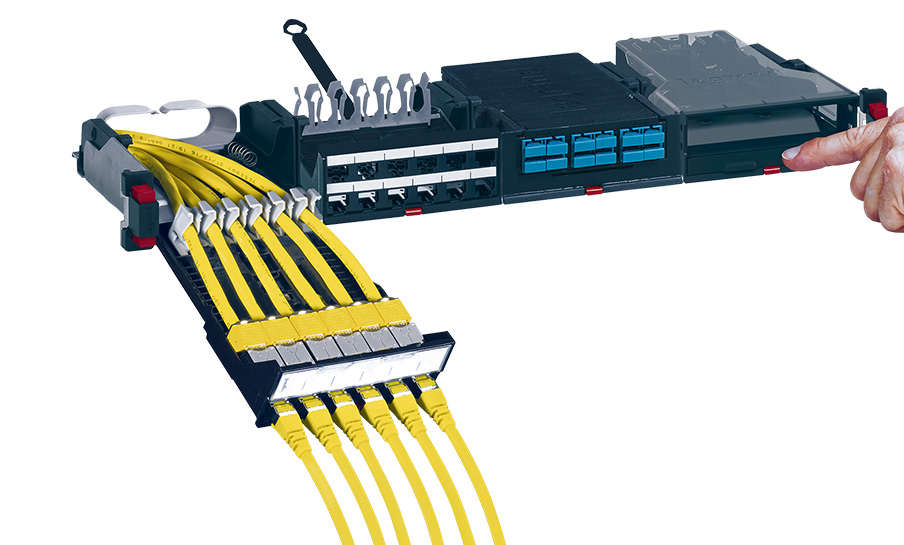 Un utente estrae un pannello patch BTicino BTNET con più cavi di rete gialli collegati.